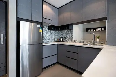 a kitchen with black cabinets and a stainless steel refrigerator at Tropics & Modern Stay - Kamala 2BR Suite CTG L502-3, Best Amenities & Beach Fun in Kamala Beach