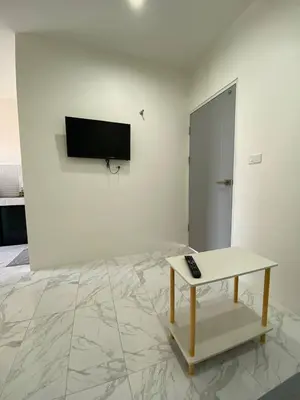 a living room with a table and a tv on a wall at Guest Room Bang Tao MMA in Ban Thalat Choeng Thale