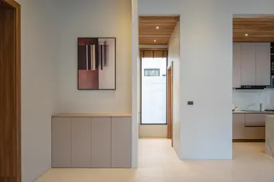 a kitchen with white cabinets and a painting on the wall at Mouana Breeze Mai Khao 4-bedroom Pool Villa 9918 in Mai Khao Beach