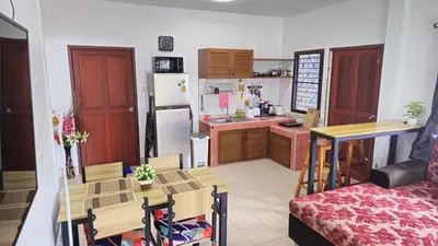 a small kitchen with a table and a refrigerator at Rawai Naiharn 3 bedroom house in Rawai Beach