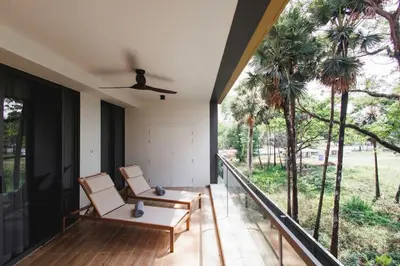 two chairs on the balcony of a house with palm trees at Beachfront 2-bd apartment Laguna in Bang Tao Beach