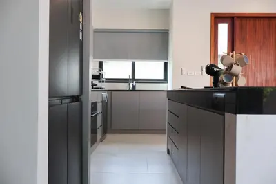 a kitchen with black cabinets and white appliances at Rawai Duplex Style Luxurious 4-BR Private Pool Villa in Rawai Beach
