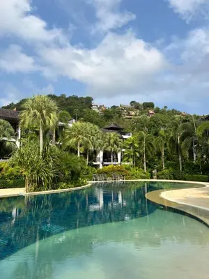 a swimming pool with palm trees in a resort at Bangtao Beach Gardens in Surin Beach