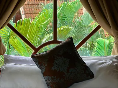 a pillow sitting on a bed in front of a window at Coco palace resort in Rawai Beach