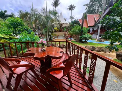 a wooden deck with a wooden table and chairs at Coco palace resort in Rawai Beach