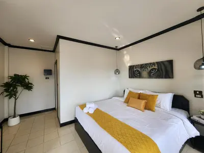a bedroom with a large white bed with yellow pillows at Wink City 2 Patong Center close to the Beach in Patong Beach