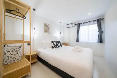 a bedroom with a large white bed and a window at Wink Centre House 10 Patong Beach in Patong Beach