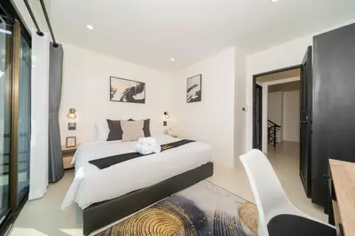 a bedroom with a large white bed and a table at Wink Centre House 10 Patong Beach in Patong Beach