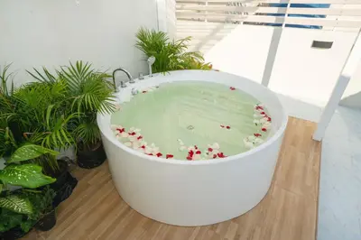 a large white bath tub sitting in a room with plants at Wink Centre House 10 Patong Beach in Patong Beach