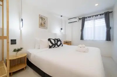 a bedroom with a large white bed and a window at Wink Centre House 10 Patong Beach in Patong Beach