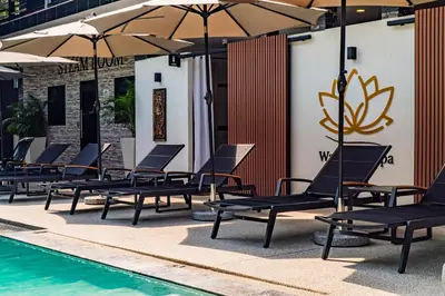a row of lounge chairs and umbrellas next to a swimming pool at Water Lily Spa Bungalows by Rawai Beach in Rawai Beach