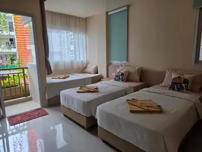 a hotel room with two beds and a couch at The Rock Patong Comfort Stay in Patong Beach
