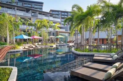 a resort pool with chairs and palm trees and a building at Seaview, 1 bd, Surin beach in Surin Beach