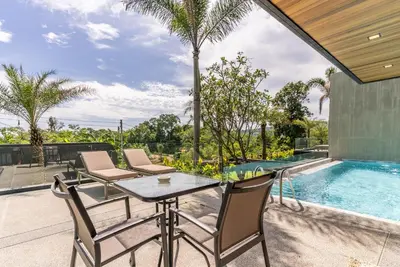 a patio with a table and chairs next to a swimming pool at Chariot by Villacarte in Layan Beach