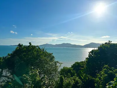 a view of the ocean with trees in the foreground at Serene Panwa beachfront in Ban Ao Makham