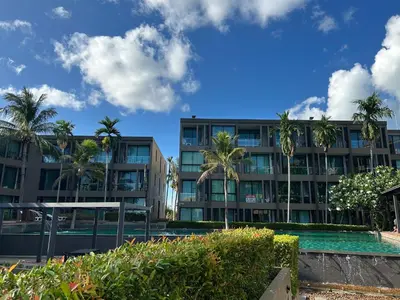 a building with palm trees and a swimming pool at Serene Panwa beachfront in Ban Ao Makham