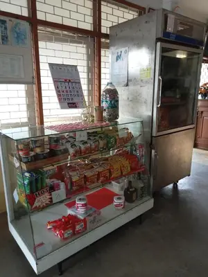 a display case in a kitchen with a refrigerator at Suksabai Hotel Phuket in Phuket Town