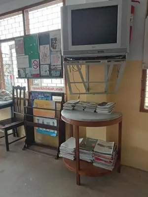 a tv on a shelf with a table with books at Suksabai Hotel Phuket in Phuket Town