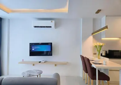 a living room with a table and a tv on a wall at Brand New 2 Bed Seaview Apartment Utopia Karon in Karon Beach