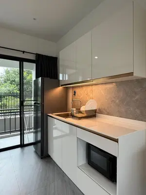 a kitchen with white cabinets and a counter with a refrigerator at P One Apartments in Phuket Town