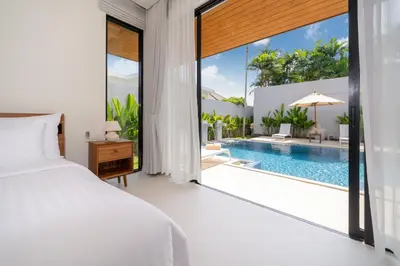 a bedroom with a bed and a swimming pool at Anchan Villas Phuket - 4 BR Signature Pool Villa by Escape Villas in Ban Phru Champa