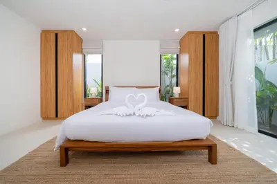 a bedroom with a white bed with a bow on it at Anchan Villas Phuket - 4 BR Signature Pool Villa by Escape Villas in Ban Phru Champa