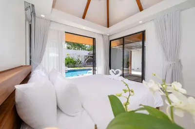 a bedroom with a white bed and a pool at Anchan Villas Phuket - 4 BR Signature Pool Villa by Escape Villas in Ban Phru Champa