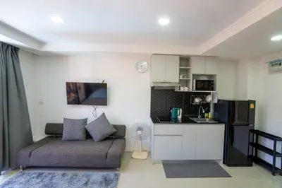 a living room with a couch and a kitchen at The Urban Tropical Apartments in Mai Khao Beach