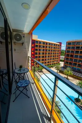 a balcony with two tables and a view of a building at The Urban Tropical Apartments in Mai Khao Beach