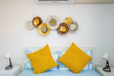 a bed with yellow pillows and hats on a wall at The Urban Tropical Apartments in Mai Khao Beach