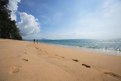 two people walking on a beach with footprints in the sand at СС619 Романтика, чудесный вид и домашний уют in Mai Khao Beach