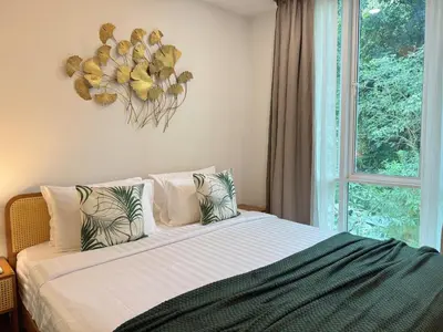 a bedroom with a bed with pillows and a window at Tropical Living Kamala Hillside in Kamala Beach