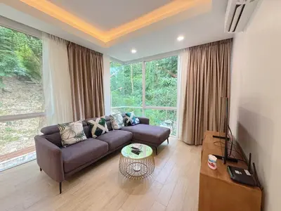 a living room with a couch and a large window at Tropical Living Kamala Hillside in Kamala Beach