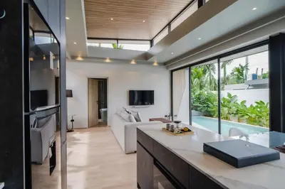 a kitchen and living room with a couch and a tv at Pangolin villa Nai Thon Beach in Nai Thon Beach