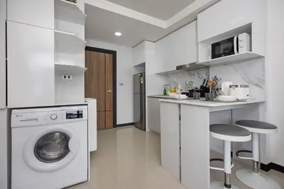 a white kitchen with a washing machine and a counter at Rawai Apartment RBC 311, near Famous Rawai Market in Phuket Town