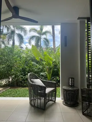 a room with chairs and a patio with palm trees at Secret Garden at Bangtao Beach in Surin Beach