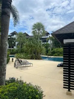 a bench next to a pool with palm trees and houses at Secret Garden at Bangtao Beach in Surin Beach