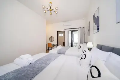 a white bedroom with two beds and a chandelier at Beachside Patong 50m or less min walk in Patong Beach