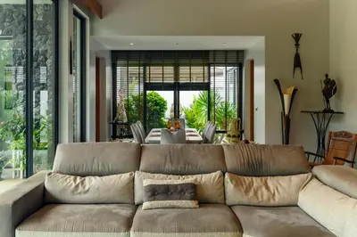 a living room with a brown couch and a table at Botanica Modern Loft by RESAVA in Bang Tao Beach