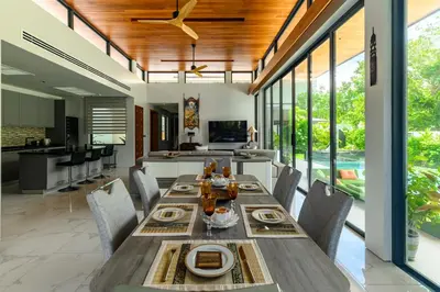 a dining room with a long table and chairs at Botanica Modern Loft by RESAVA in Bang Tao Beach