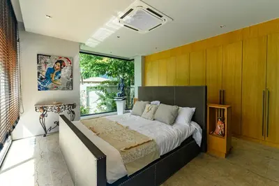 a bedroom with a large bed and a large window at Botanica Modern Loft by RESAVA in Bang Tao Beach
