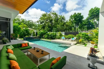 a living room with a green couch and a pool at Botanica Modern Loft by RESAVA in Bang Tao Beach