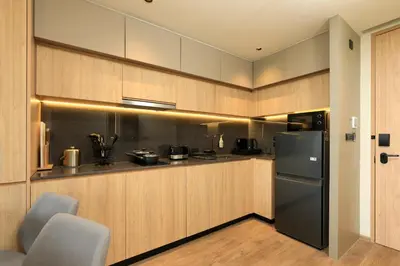 a kitchen with wooden cabinets and a black refrigerator at New 1bdr Apartment Layan C518 in Ko Kala