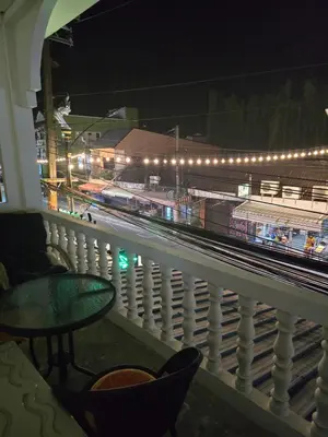 a balcony with a view of a train station at night at Kata Cozy Guest Room in Kata Beach