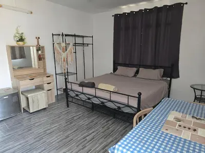 a bedroom with a bed and a tv and a table at Kata Cozy Guest Room in Kata Beach