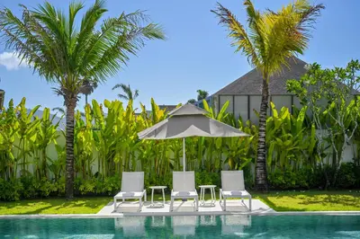 a pool with chairs and an umbrella and palm trees at Asherah Villa By Asherah Team in Ban Phru Champa