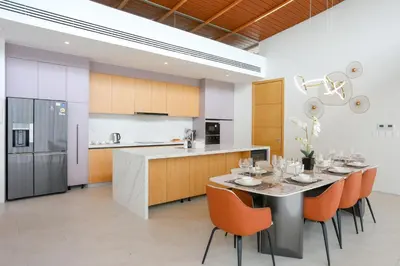 a kitchen with a table with orange chairs and a counter at Asherah Villa By Asherah Team in Ban Phru Champa