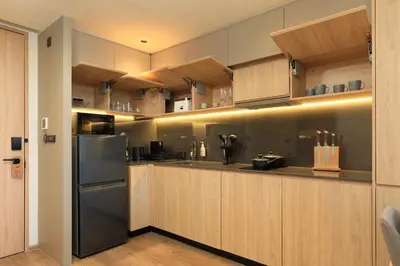 a kitchen with wooden cabinets and a stainless steel refrigerator at New 1 bdr Apartment near Layan beach C610 in Ko Kala