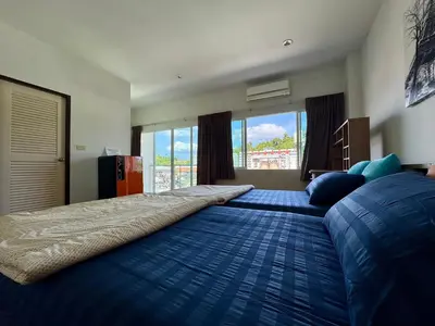 a bedroom with a large bed with a blue blanket at Ananas Central Phuket Hostel in Ban Ket Ho