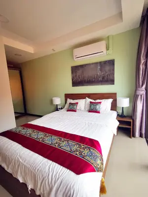 a bedroom with a large bed with red and white sheets at 1 bedroom Naiharn Beach Condo in Rawai Beach